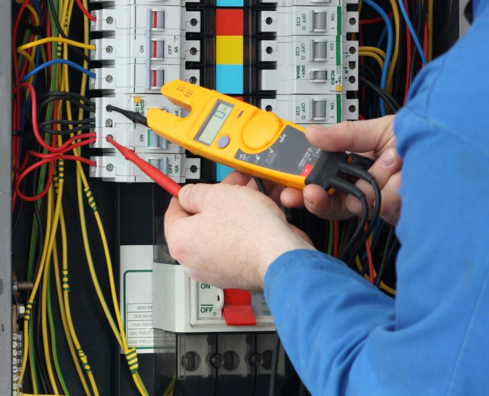 Electrician testing for voltage in a fuse box